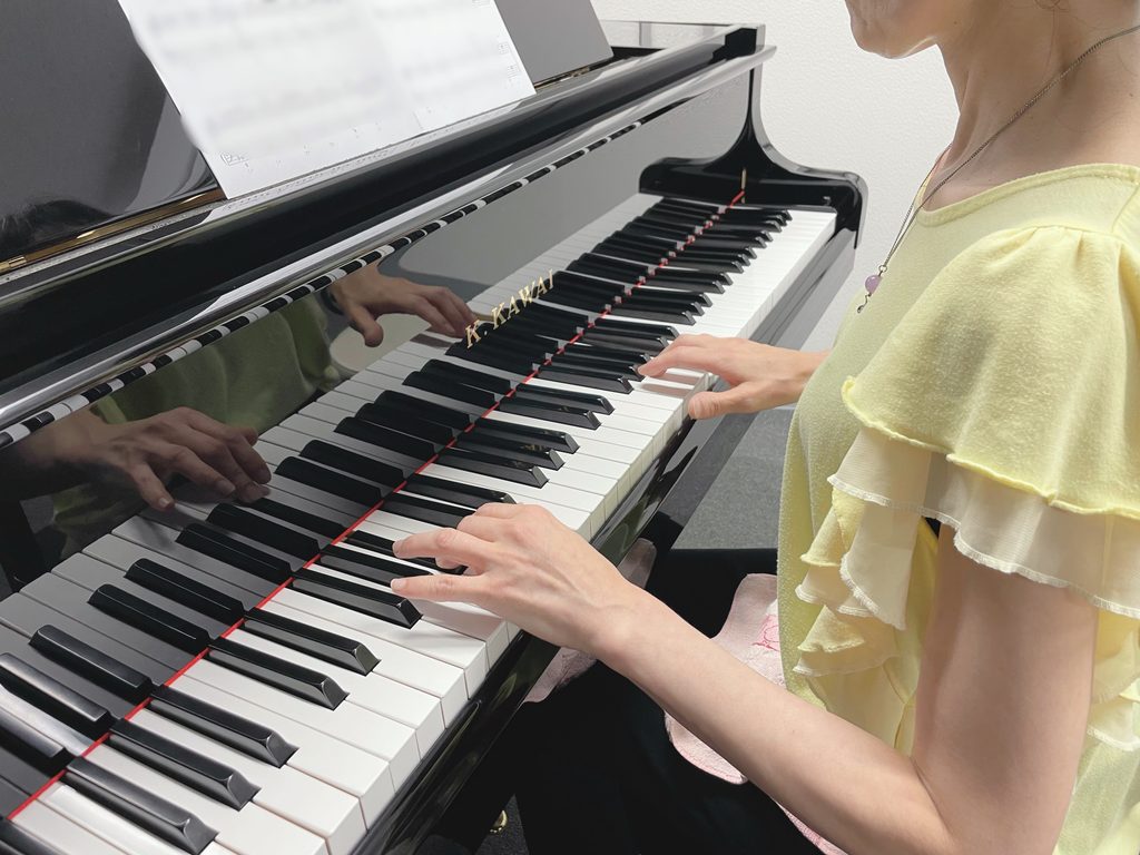 大人の女性がピアノを弾いている手元
